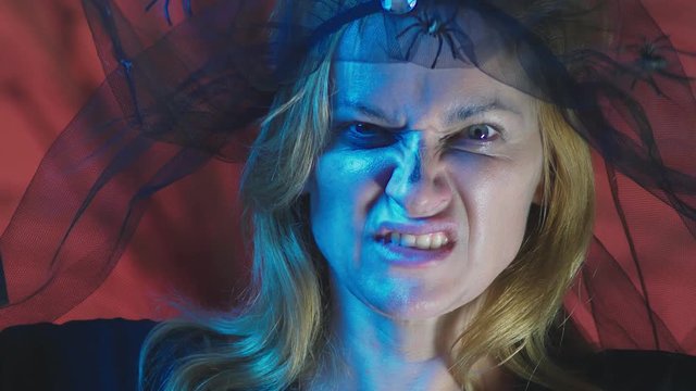 4k, slow motion, Halloween. Woman in costume of a terrible witch, swears looking at the camera, close-up