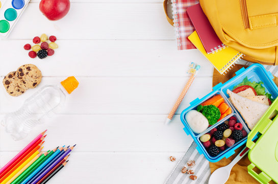 Lunch box on white wooden background near school accessories and backpack.jpg