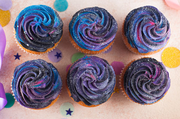 Top view of cupcakes with galaxy whipped cream on party background