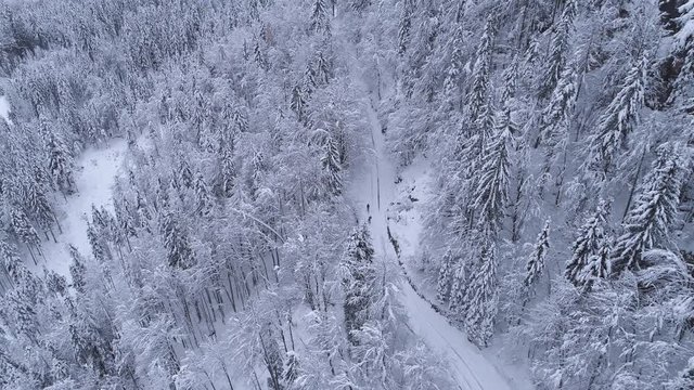 Aerial - Couple ski walking on snowy road and one of them using ski pulk