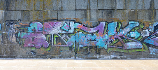 Fragment of graffiti drawings. The old wall decorated with paint stains in the style of street art culture. Colored background texture in cold tones