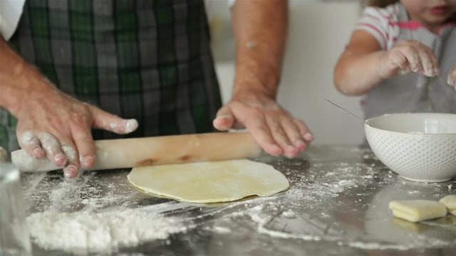 Man Rolling Out Dough On Kitchen Table. He Is A Chef In This Kitchen.