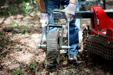 Mechanic repairs dirty and rusty brush cutter, tractor attachment