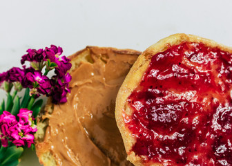 Toasted sourdough english muffin with strawberry jam and peanut butter and floral garnish