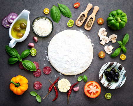 The ingredients for homemade pizza on dark stone background.