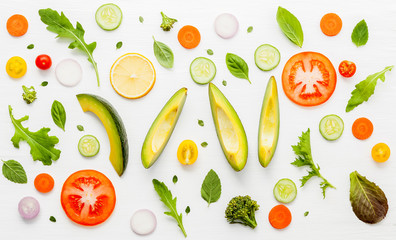 Food pattern with raw ingredients of salad, lettuce leaves, cucumbers, tomatoes, carrots, broccoli, basil ,onion and lemon flat lay on white wooden background.