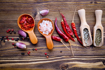 Various herbs and spices in wooden spoons on wooden background.