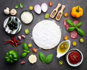 The ingredients for homemade pizza on dark stone background.