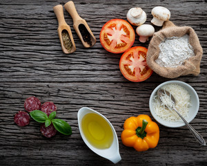 The ingredients for homemade pizza on shabby wooden background.