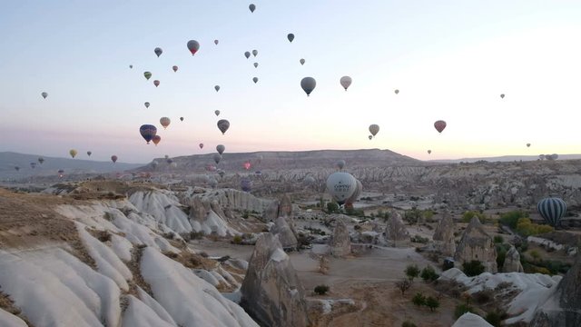 Goreme, Turkey - November 4, 2017: Camera still view of many flying tourist hot air balloons floating at morning sunrise in beautiful Cappadocia landscape
