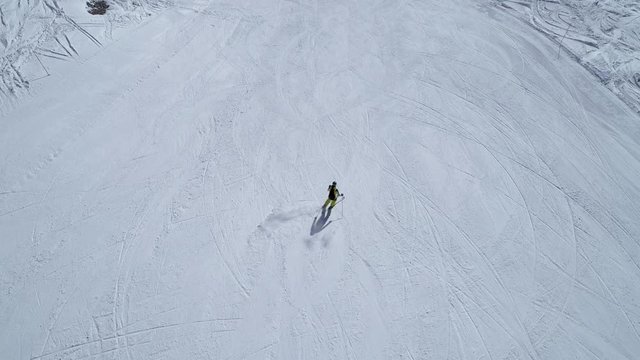 Aerial - Follow shot of good alpine skier skiing down the wide empty ski slope