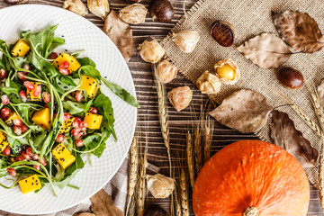 Food flat lay. Top view. Salad with mango, roasted pumpkin, arugula, pomegranate seeds lying on...