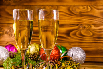 Two wineglasses with champagne and different christmas decorations on wooden table