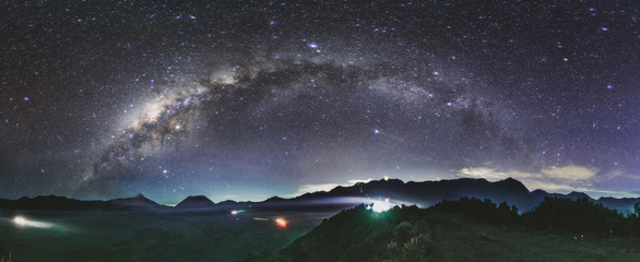 Panoramic astrophotography milky way above greenery field