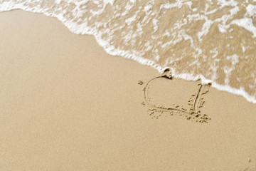Heart in the sand on a beach with waves washing over
