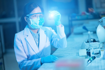 Young female scientist or researcher in medical lab with test tube centrifuge and flask