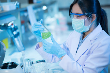 Young female scientist or researcher in medical lab with test tube centrifuge and flask