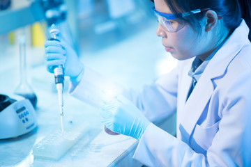 Young female scientist or researcher in medical lab with test tube centrifuge and flask