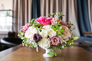 Arrangement of fresh flowers in pastel colors with a bright accent. Wedding background. table in a restaurant. different varieties of garden and shrub roses in a light vase on wooden table