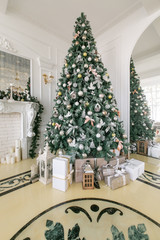 Presents and Gift boxes under Christmas Tree. Beige boxes with ribbon bow. New year decorated house interior. Winter Holiday concept.