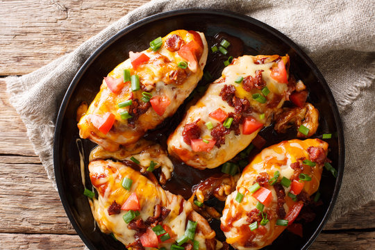 Delicious Monterey chicken breast baked with cheese, bacon, tomatoes and barbecue sauce close-up. Horizontal top view