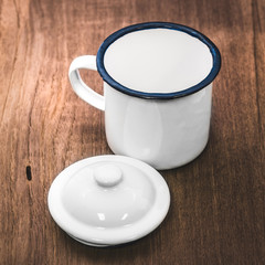 Vintage mug style on wooden background. Retro tea cup made from tin material.