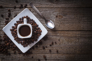 Square coffee cup on wooden table with coffee beans, top view