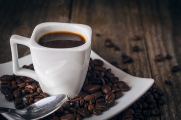 Square coffee cup on wooden table with coffee beans