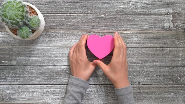 Person holding a pink heart shaped box. Valentine's Day theme.