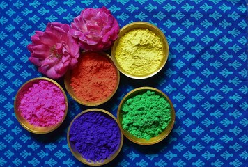 Fototapeta na wymiar Vibrant colorful powder in brass bowls with rose flowers/Holi festival