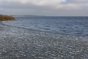 the background image of the cold North sea autumn day, frozen near the shore, small round pieces of ice