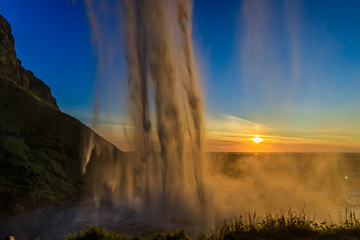 Behind of waterfall at sunset