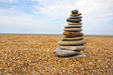 Stones pyramid on sand symbolizing zen, harmony, balance. Sea in the background