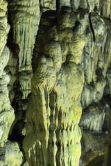 the background image is green-yellow stalactites and stalagmites that grow in a dark cave, glistening with moisture and covered with moss in cave of Zeus