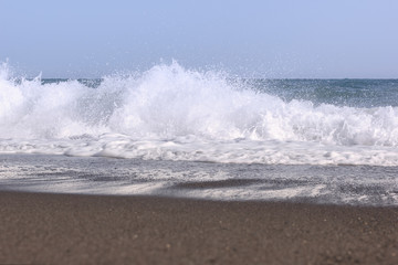 white splashes of waves in the sea rolling on the sandy shore
