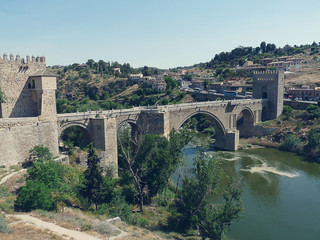 Fototapeta na wymiar ancient bridge leading to the fortress of Toledo across a stormy river in retro style