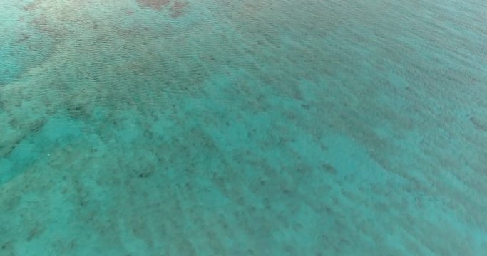 Aerial view above turquoise ocean water with reef, Caribbean