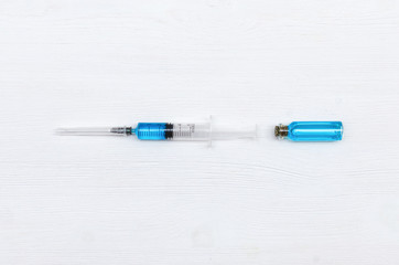 Syringe and ampoule with blue liquid medicine on the doctor table.