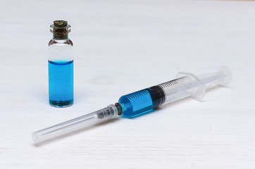 Syringe and ampoule with blue liquid medicine drug on the doctor table.