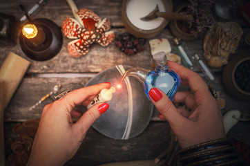 Witch woman is preparing a magic potion on paranormal table background. Witchcraft concept.