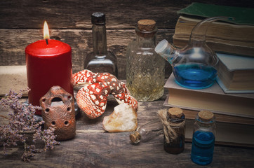 Magic potion in the vial on the wizard table. Witchcraft concept. Essential oil bottles and old books. Herbal medicine.