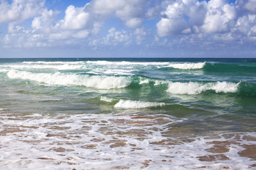 Beautiful waves on a blue green ocean with white foam blue sky with clouds rest holiday on nature beach paradise