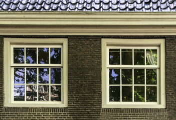 Two white vintage sash windows in brown brick wall. Retro building in Amsterdam, Netherlands, architectural elements.
