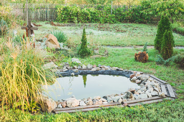 Beautiful classical design garden fish pond in a well cared backyard gardening background