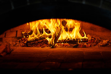 Pizza in the oven. Beautiful fire burns in the furnace. Cooking pizza in the cafe.
