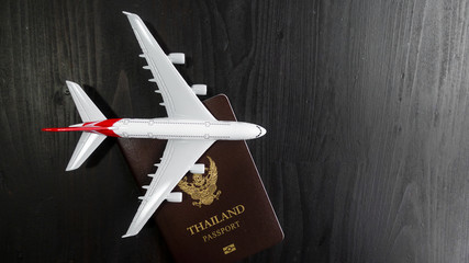 Airplane model and passport on wooden desk, ready travel concept