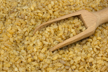 Bulgur or couscous scattered with a wooden scoop