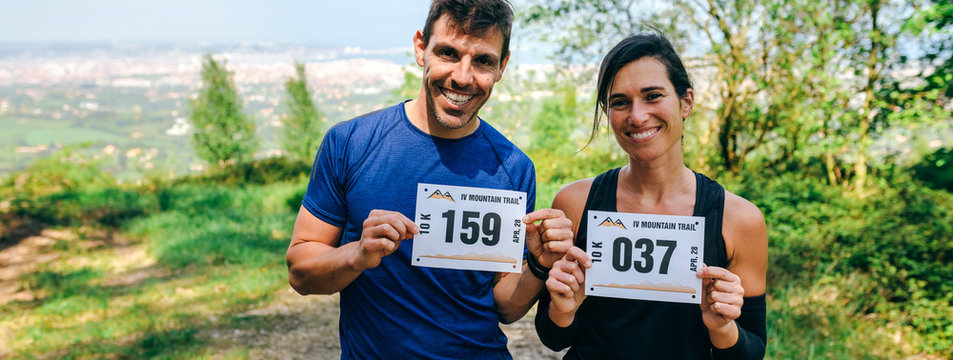 Smiling Young Man And Woman Showing Their Trail Race Number Outdoors