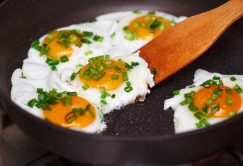 Fried eggs with an onion on a wooden blade.