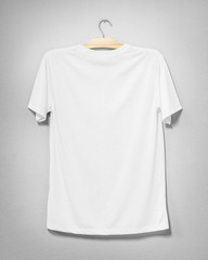 White shirt hanging on cement wall. Empty clothing for design. Back view.